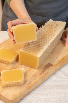 a person is cutting cheese on top of a wooden board with honeycombs around it