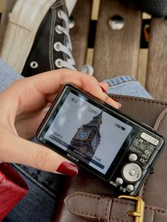 a person holding a cell phone in their left hand and sitting on a wooden bench