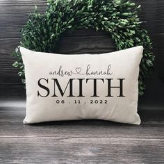 a personalized pillow with the names of two people on it and a wreath behind it