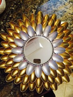 a mirror that is sitting on top of a marble counter with gold and silver petals