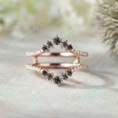 a diamond ring with two rows of diamonds on it, sitting next to a pine tree