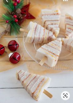 several small sandwiches are on a plate with christmas decorations and candy in the back ground