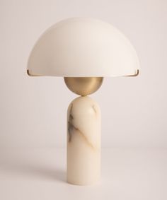 a table lamp with a white marble base and a gold dome light shade on top