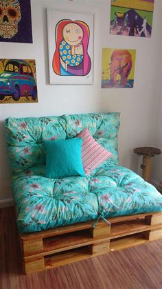 a futon bed made out of pallets in a room with pictures on the wall