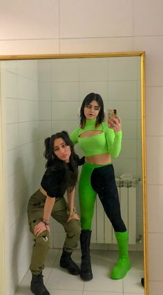 two women are taking a selfie in the mirror while wearing green clothing and black boots