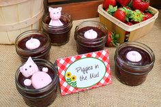 there are many jars with chocolate puddings in them and some strawberries on the table