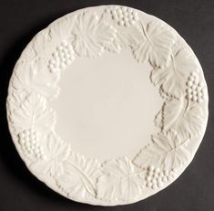 a white plate with grapes and leaves on it