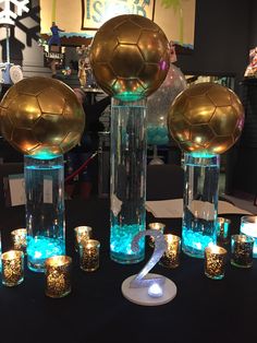 a table topped with vases filled with candles and soccer balls