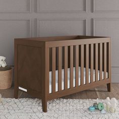 a baby crib sitting on top of a wooden floor next to a stuffed animal