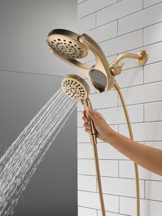 a person is holding the shower head and spraying it with water from the faucet