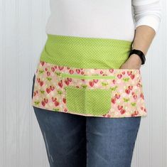 a woman is wearing an apron with strawberrys on it and has her hands in her pockets