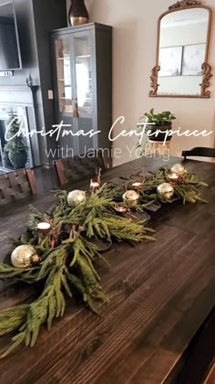 a wooden table with candles and greenery on it in front of a fire place