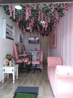 a living room with pink furniture and flowers hanging from the ceiling