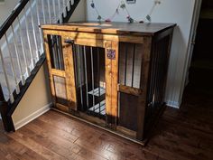 a wooden dog crate sitting on top of a hard wood floor next to a stair case