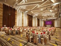 a banquet hall with tables and chairs covered in gold cloths, decorated with red and white centerpieces