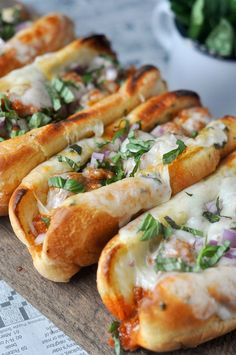 several hot dogs with toppings are lined up on a table