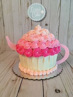 a cupcake decorated with pink and white icing on top of a cake plate