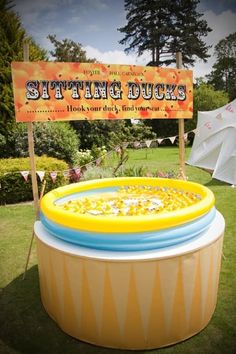 an inflatable swimming pool is set up on the lawn with a sign that says sitting ducks