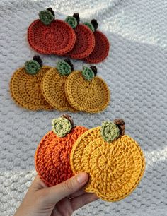 there are crocheted pumpkins on the table and one is holding it up