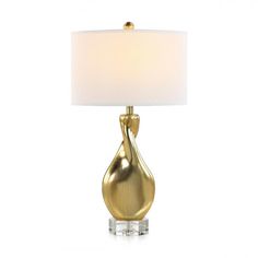 a gold table lamp with a white shade on the base and a light bulb attached to it