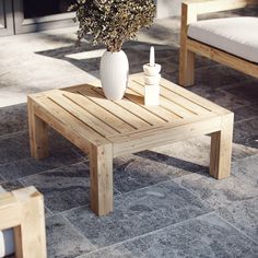 a white vase sitting on top of a wooden table next to two chairs and a bench