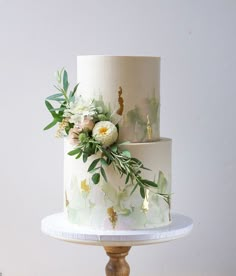 a three tiered cake decorated with flowers and greenery