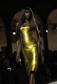 a model walks down the runway in a yellow dress