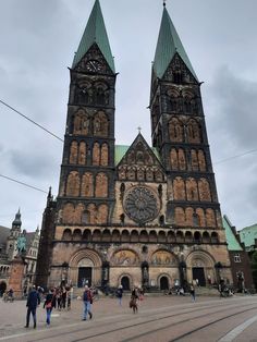 people are walking around in front of an old church