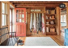 a room with wooden walls and lots of coats hanging on the door, next to a bench