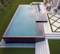 an aerial view of a pool with steps leading up to it and grass in the background