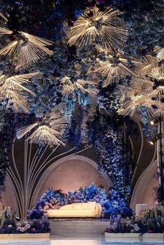 an elaborately decorated stage with blue flowers and greenery