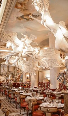 the interior of a restaurant with many tables and chairs in front of large paintings on the ceiling