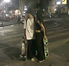 two skateboarders are standing on the street at night with their boards in hand