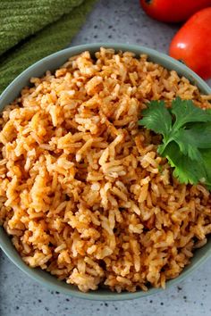 a bowl filled with brown rice next to tomatoes and green garnish on the side