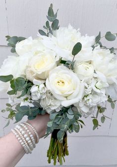 a bouquet of white flowers is being held by someone's hand