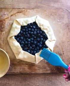 a blueberry pie being made with a plastic brush