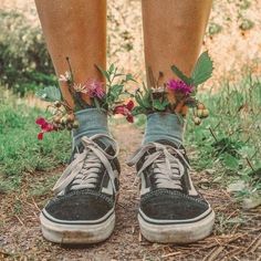 a pair of shoes with flowers on them are standing in front of grass and dirt