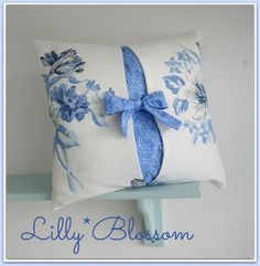 a blue and white pillow with a bow on the front is sitting on a shelf