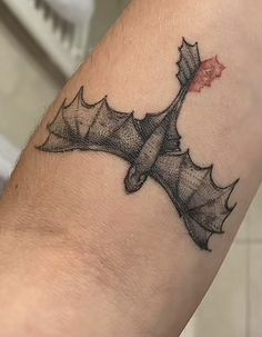 a tattoo on the arm of a person with a bat and leaves design on it