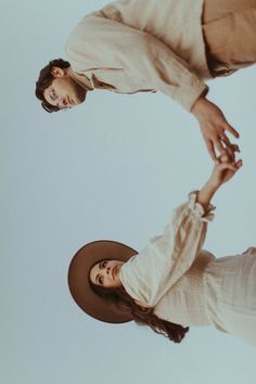 two people standing next to each other in front of a blue sky with one holding the other's hand