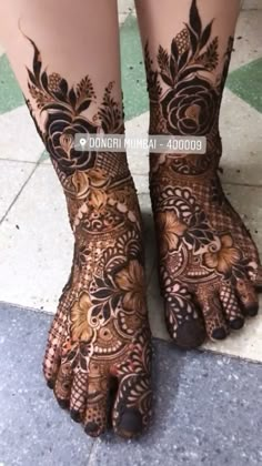 the legs and feet of a woman with henna tattoos on their hands, both covered in floral designs