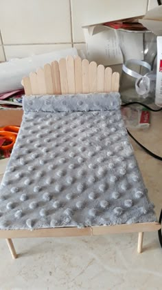 a bed made out of popsicle sticks sitting on top of a counter next to scissors