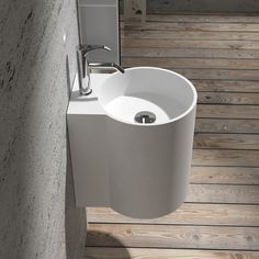 a white sink sitting on top of a wooden floor next to a wall mounted faucet