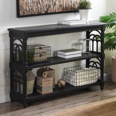 a black shelf with baskets and plants on it in front of a wall mounted painting