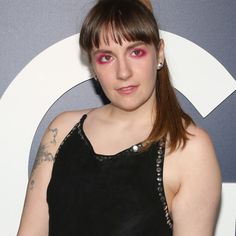 a woman with pink eyeliners standing in front of a wall