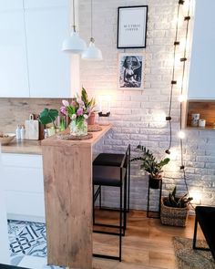 a kitchen with white brick walls and wooden flooring, two bar stools in front of the counter