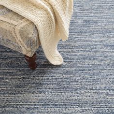 a bed with a blanket on top of it next to a wooden footstool