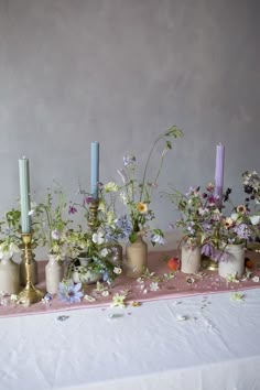 a table topped with vases filled with different types of flowers and candles next to each other