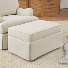 a white chair and footstool in a room with a rug on the floor