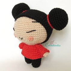 a crocheted doll with black hair and red shirt